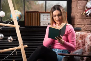 Beautiful young woman reading book over Christmas background. High quality photo
